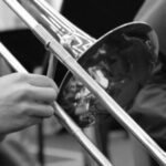 person playing trumpet in grayscale photography