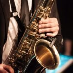 person in white dress shirt holding saxophone