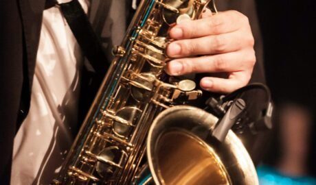 person in white dress shirt holding saxophone