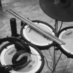 grayscale photo of drumsticks on electric drum kit