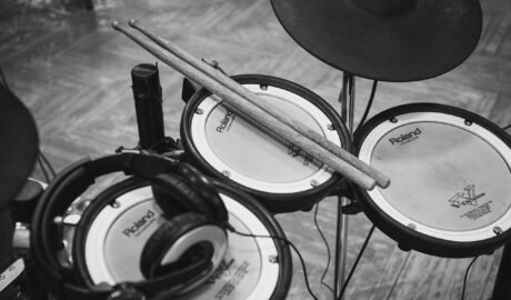 grayscale photo of drumsticks on electric drum kit