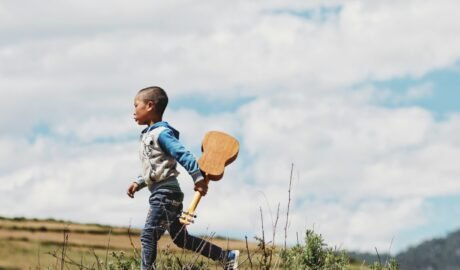 boy running while holding ukelele