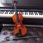 brown violin with brown violin bow beside white electronic keyboard