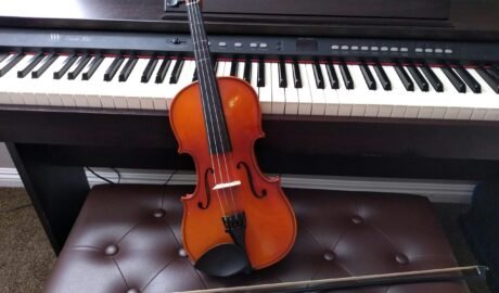 brown violin with brown violin bow beside white electronic keyboard