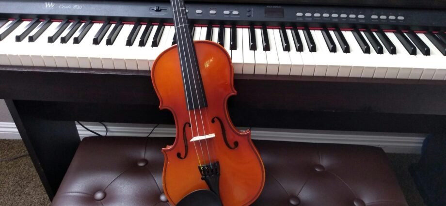 brown violin with brown violin bow beside white electronic keyboard