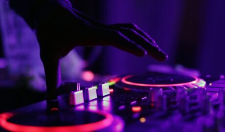 selective focus silhouette photography of man playing red-lighted DJ terminal